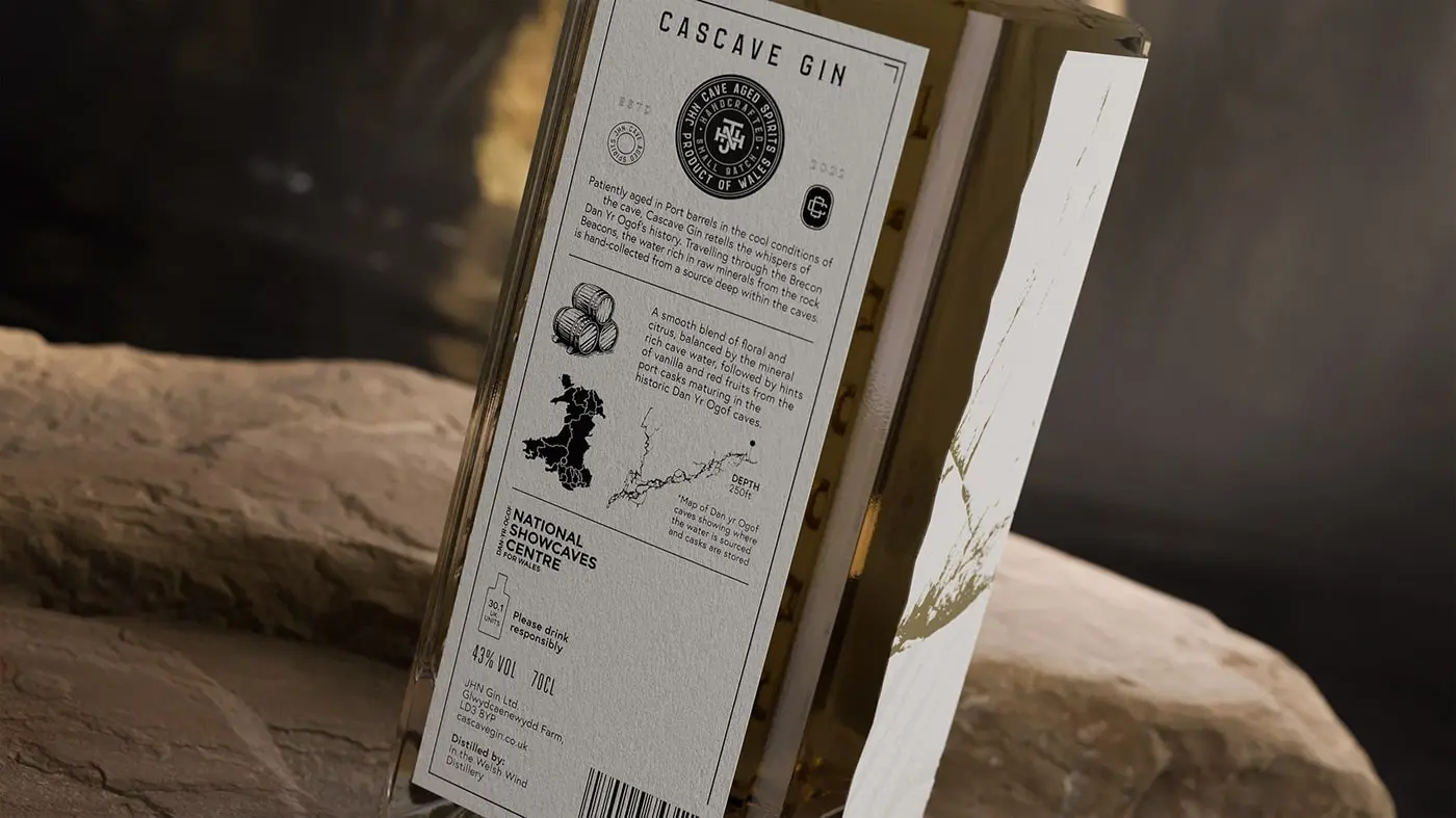 A bottle of Cascave Gin with intricate deboss detailing that resembles the rocky surfaces of Welsh caves, fluted and pressed foils glinting like mineral deposits, set against a palette inspired by the natural colors of the Brecon Beacons.