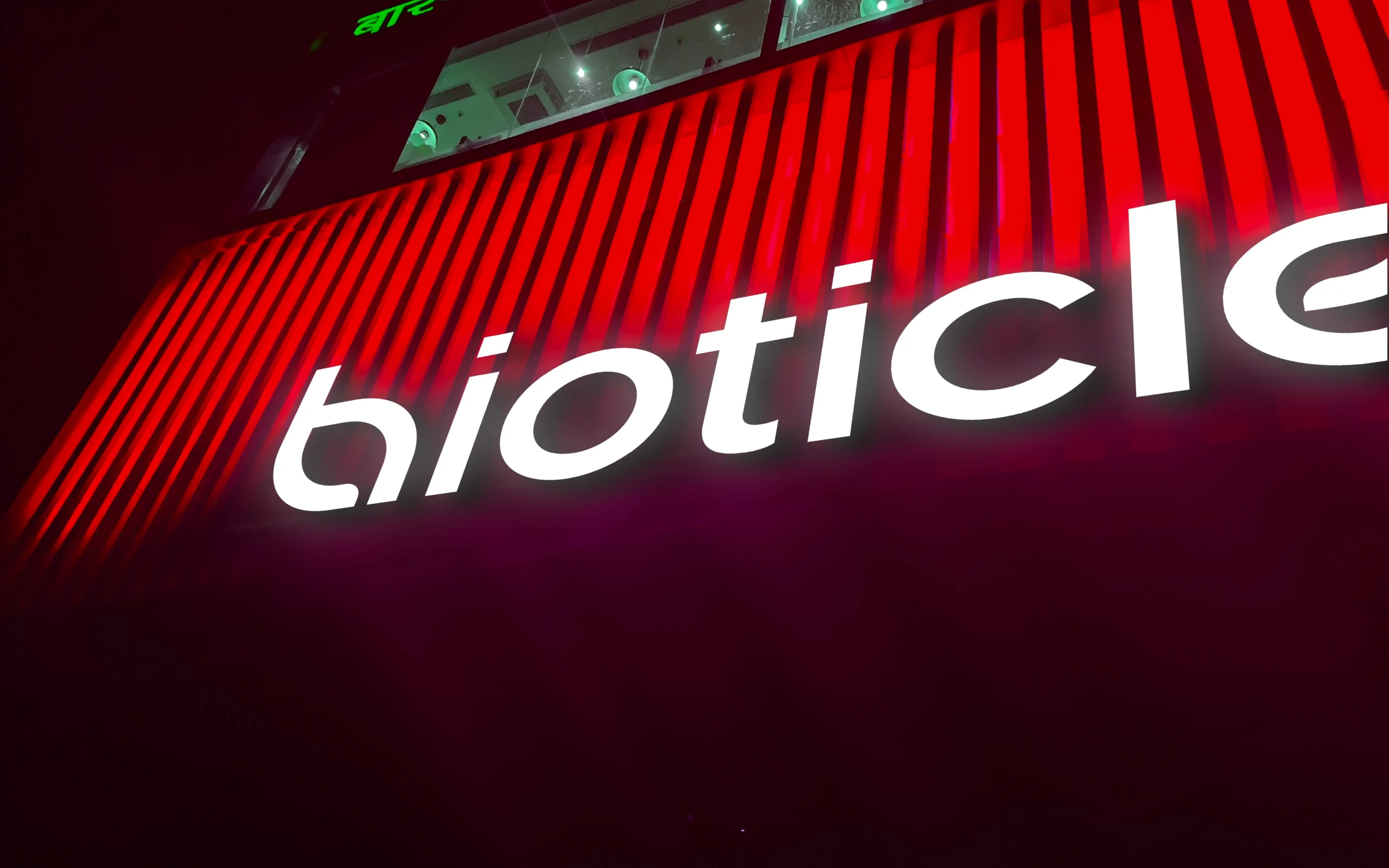 Bioticle illuminated signage on red facade at night - environmental branding and logo sign design